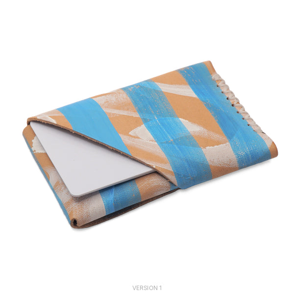 A slim leather card holder wallet with a geometric pattern of blue, tan, and white brushstrokes, shown holding a white card. The image is labeled 'VERSION 1' at the bottom.