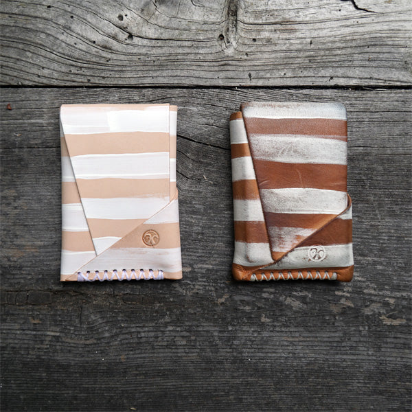 new and aged natural vegetable tanned wallets with white painted stripes next to each other