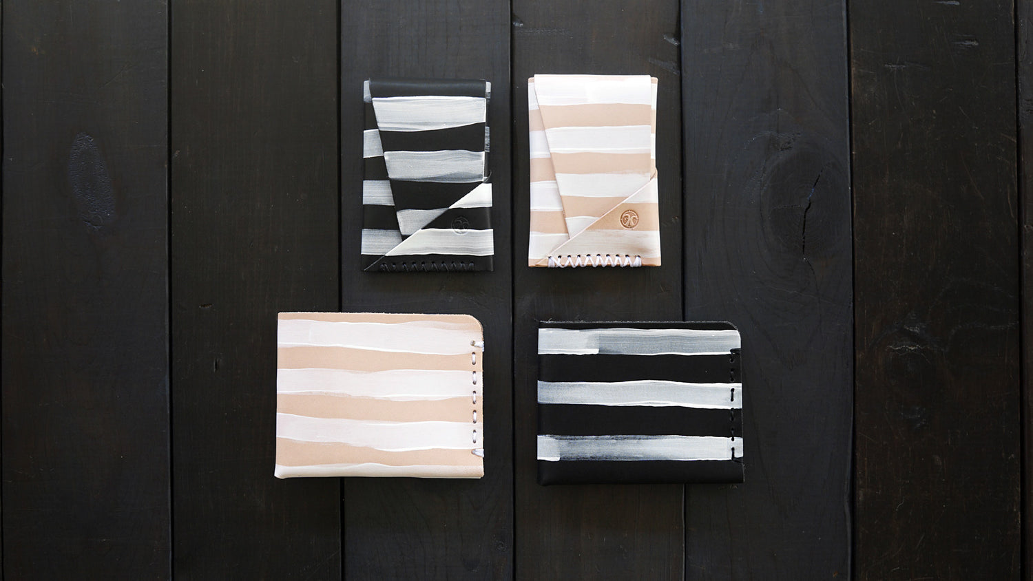 Four wallets with hand-painted white stripes on wood background